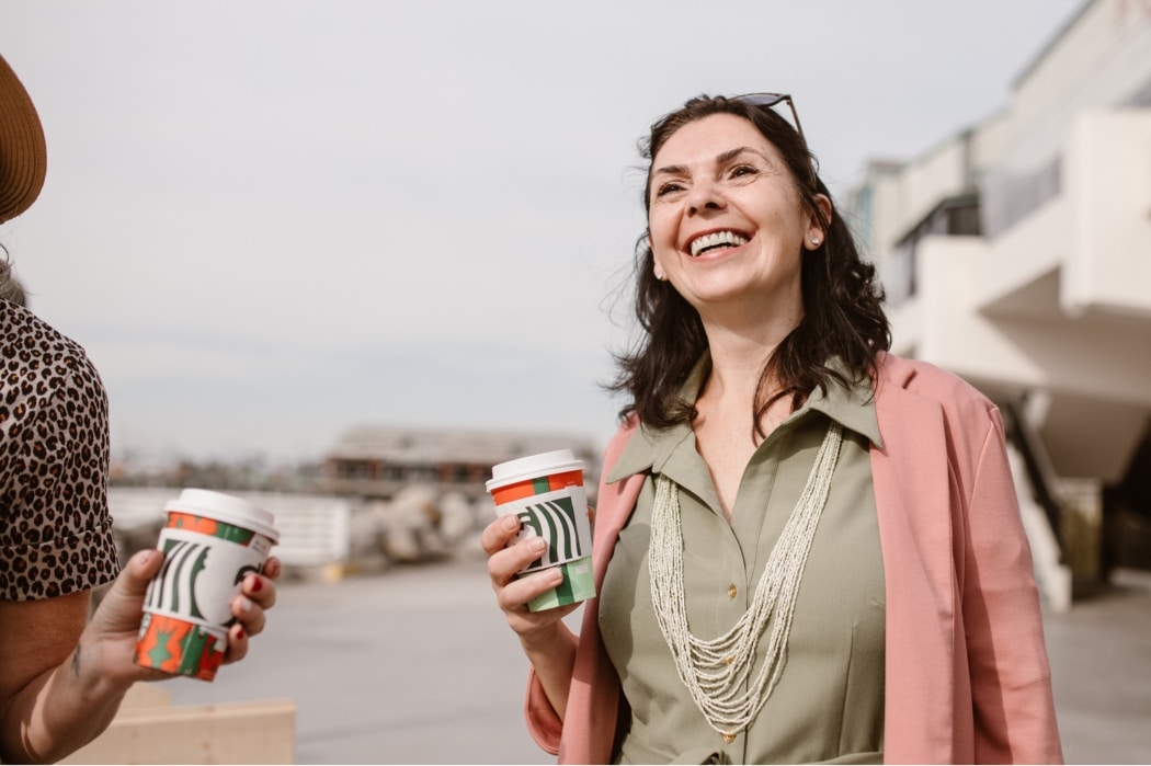 A woman enjoys a coffee with her friend, free from the shackles of bladder problems.